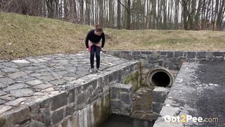 Brunette sprays her piss over the edge of a public drainage pipe - Pee